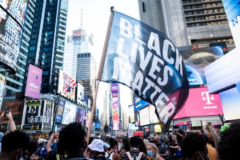 MANHATTAN, NY - July 26: A protester holds a large flag that says, "Black Lives Matter" in Times Square in New York. Many people were wearing masks and observing social distancing due to the coronavirus pandemic. (Photo by Ira L. Black/Corbis via Getty Images)