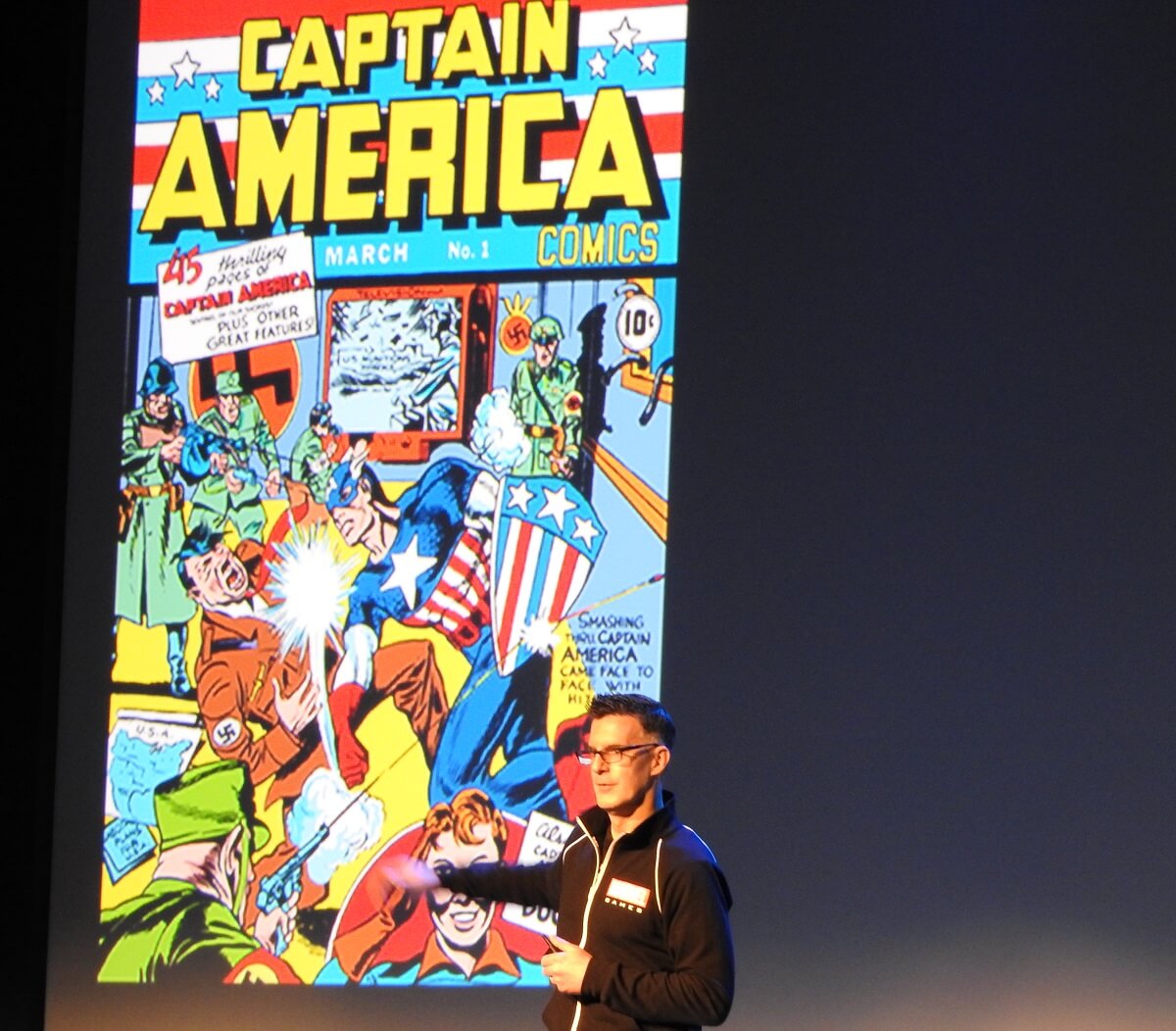 Bill Rosemann standing next to an image of the original Captain America.