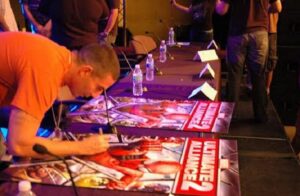 Daniel Dilallo signs a poster for a video game he worked on.