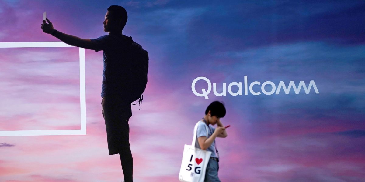 A woman walks past a sign advertising Qualcomm at Mobile World Congress (MWC) in Shanghai, China