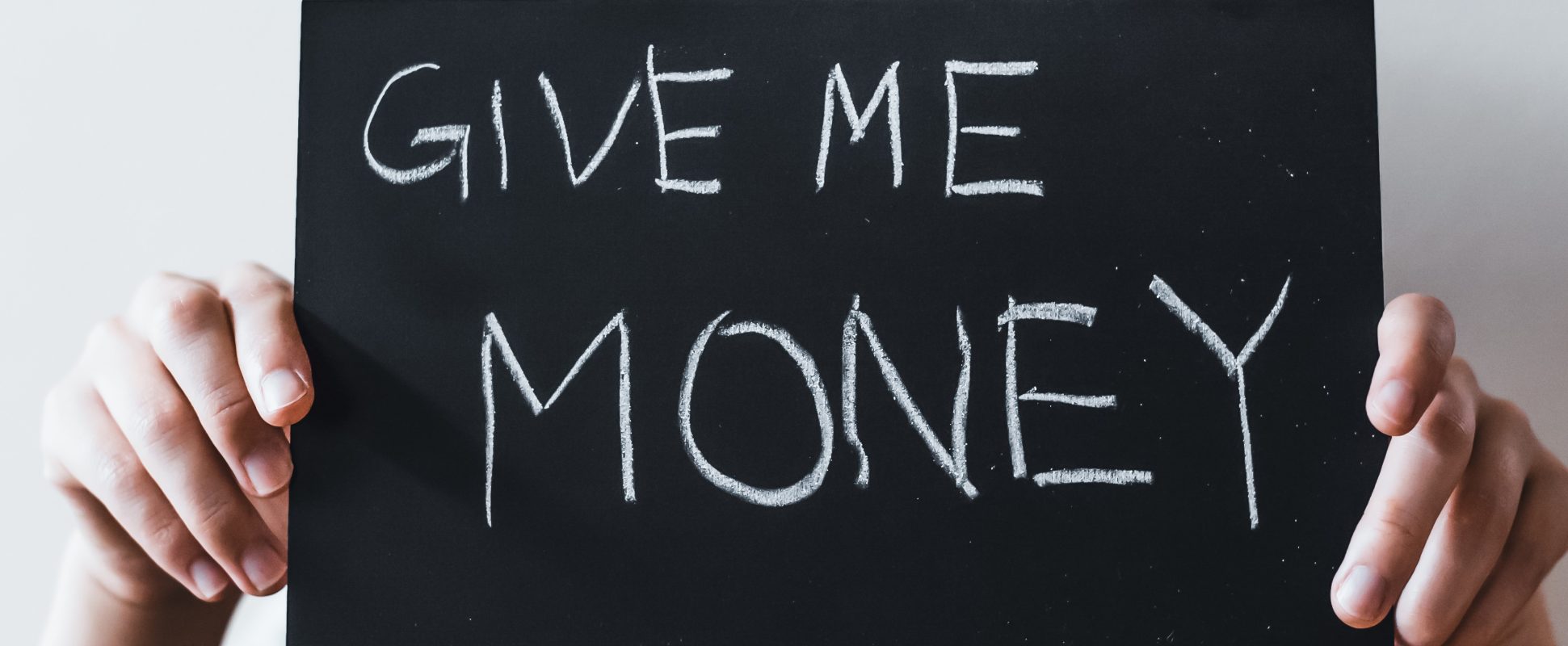 hands holding a sign saying give me money, representing ransomware