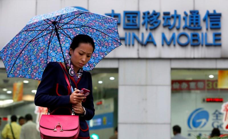 FILE PHOTO: A woman uses her mobile phone in front of a China Mobile office in downtown Shanghai October 22, 2012.   REUTERS/Aly Song/File Photo