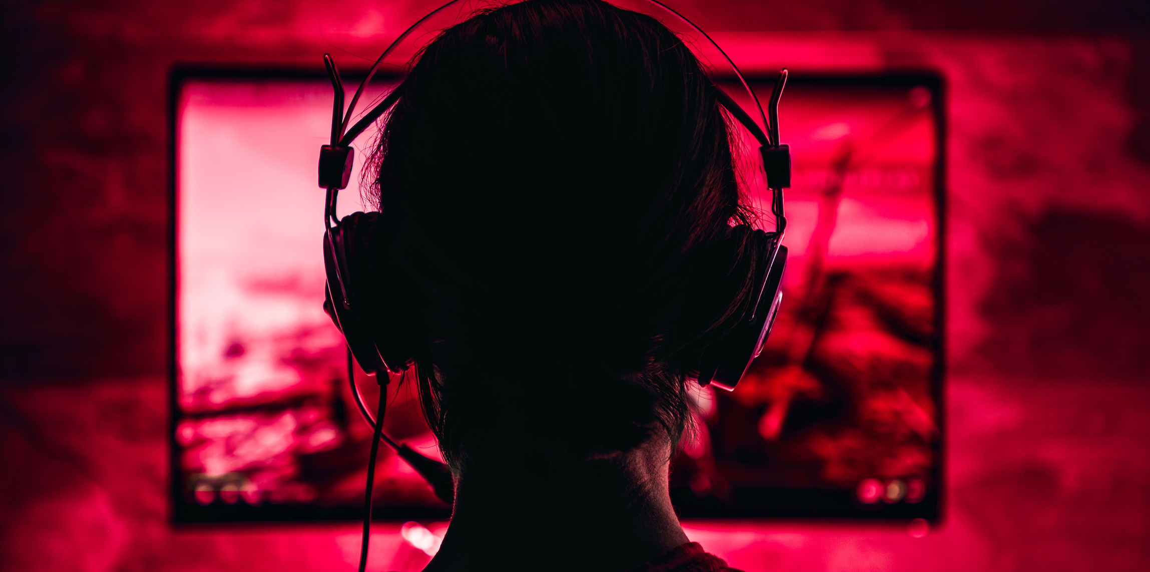 Woman wearing headphones playing video games late at night
